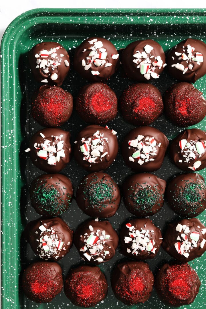 green speckled tray of oreo truffles that have been decorated with crushed candy canes.