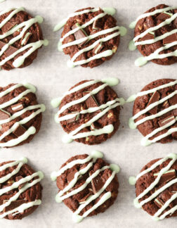 parchment lined baking sheet with chocolate cookies drizzled with green icing