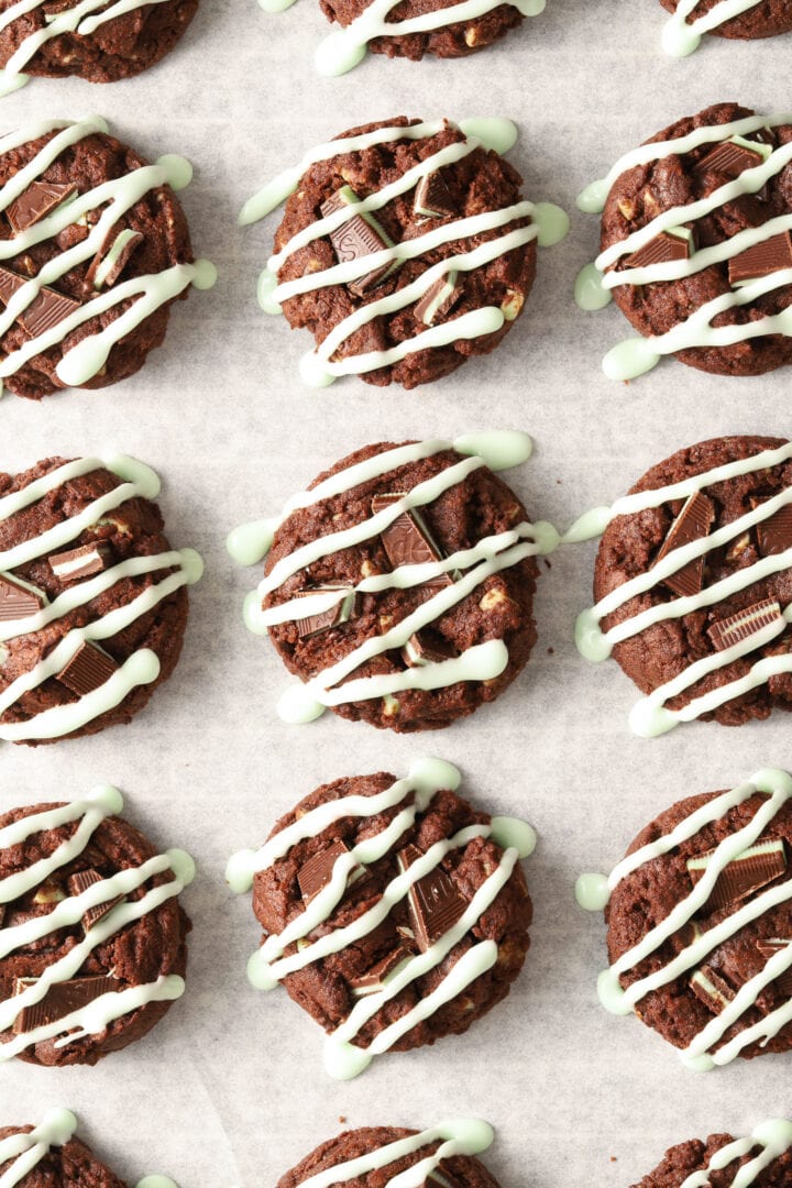 parchment lined baking sheet with chocolate cookies drizzled with green icing