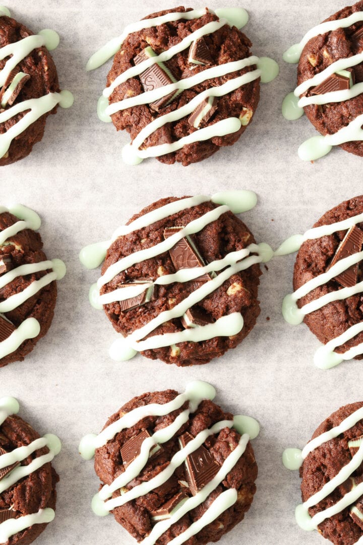 parchment lined baking sheet with chocolate cookies drizzled with green icing