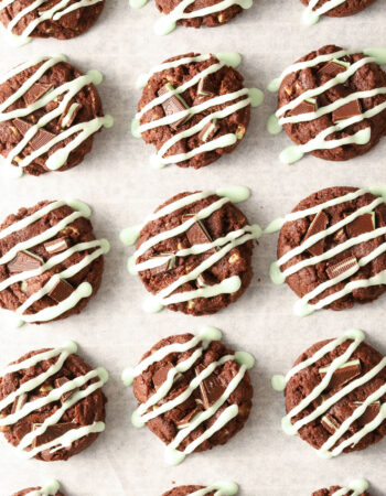 parchment lined baking sheet with chocolate cookies drizzled with green icing