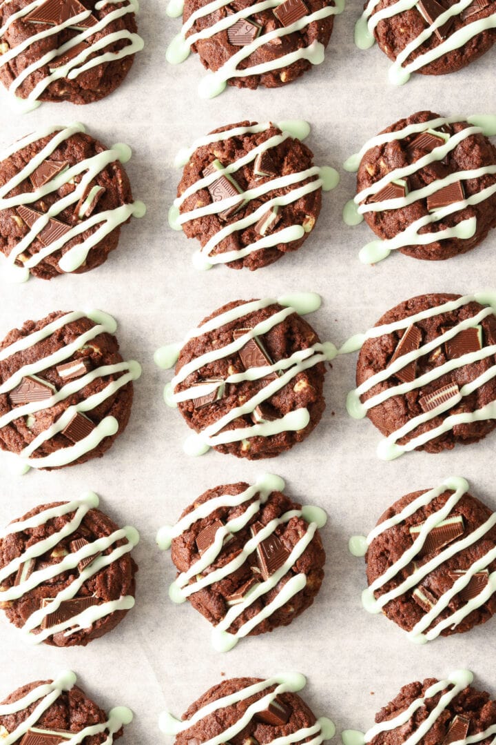 parchment lined baking sheet with chocolate cookies drizzled with green icing