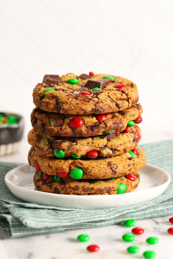 stack of 5 christmas chocolate chip cookies with red and green candies