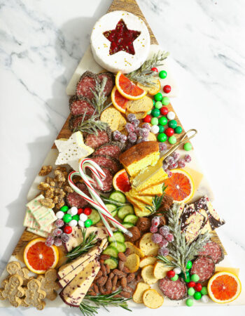 christmas tree shaped snack board topped with sweet, salty and savory snacks.