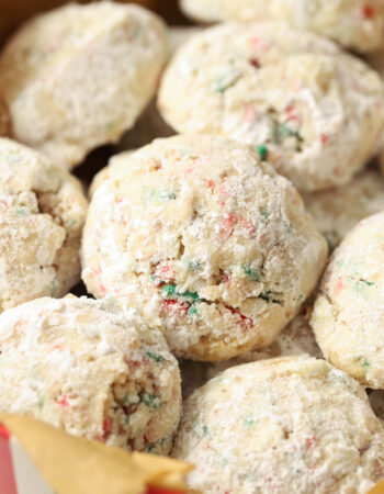 pile of christmas wedding cookies in a red, white and green striped tin