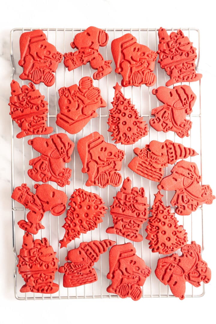 several red velvet cut out cookies shaped like snoopy and christmas trees.