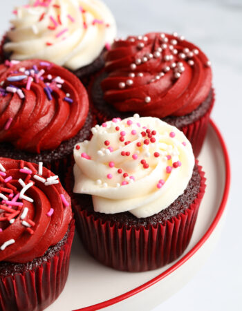 white porcelain tray of red velvet cupcakes with red and white frosting.