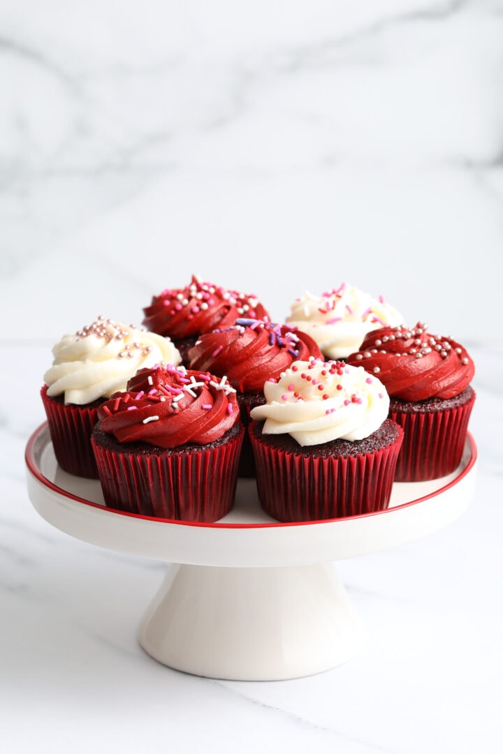 white porcelain tray of red velvet cupcakes with red and white frosting.