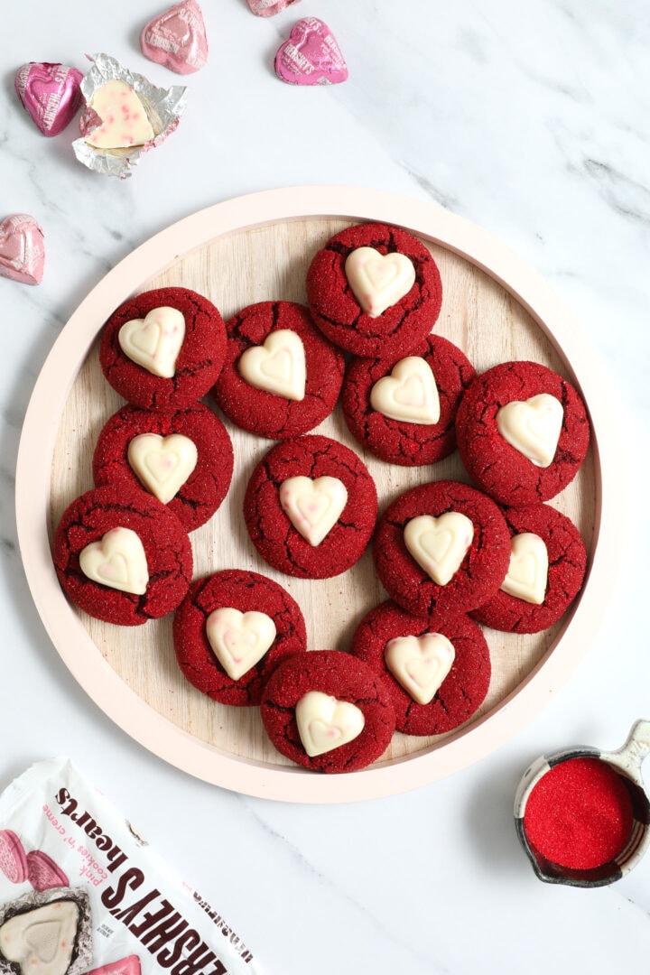 pink wooden plate of red velvet cookies with white chocolate heart candies in the center