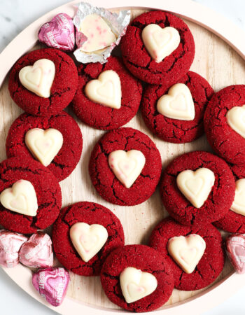 pink wooden plate of red velvet cookies with white chocolate heart candies in the center