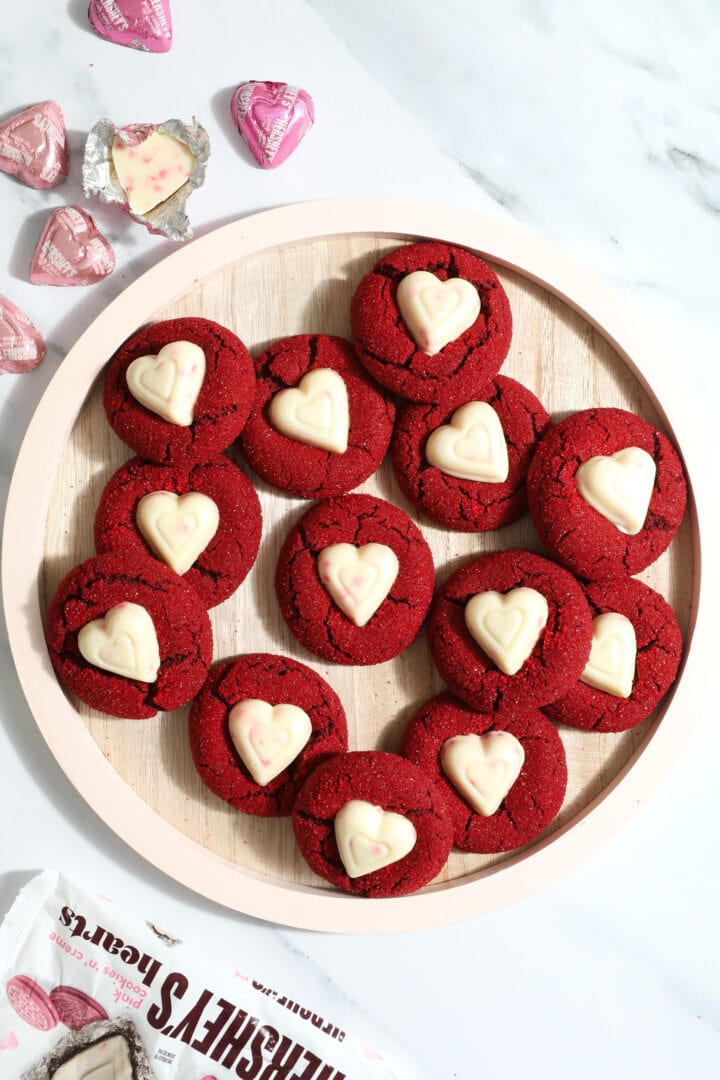 pink wooden plate of red velvet cookies with white chocolate heart candies in the center
