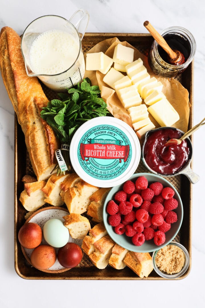 a tray of ingredients to make French toast crostini, including ricotta cheese, eggs, and raspberry jam.