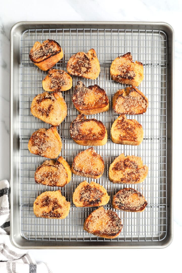 a cooling rack filled with French toast crostini that has been covered with cinnamon sugar.