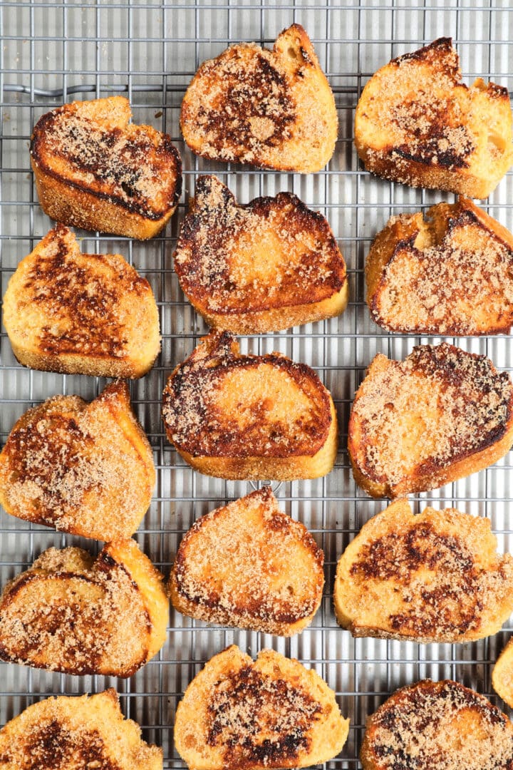 a cooling rack filled with French toast crostini that has been covered with cinnamon sugar.