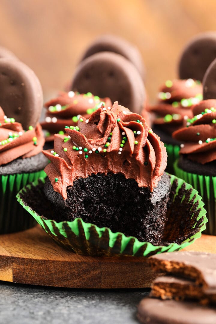 unwrapped chocolate cupcake in a green wrapper, with chocolate frosting and green sprinkles.