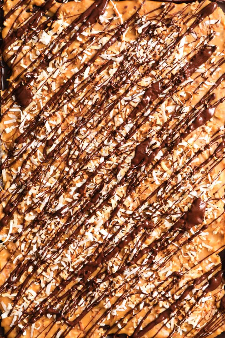 top view of coconut caramel cookie bars that are topped with toasted coconut and drizzled in chocolate.