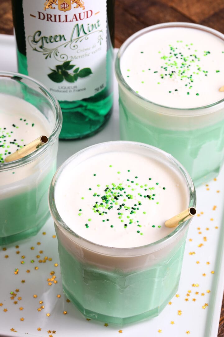 green mint milkshakes with creamy topping, green sprinkles and gold straws.