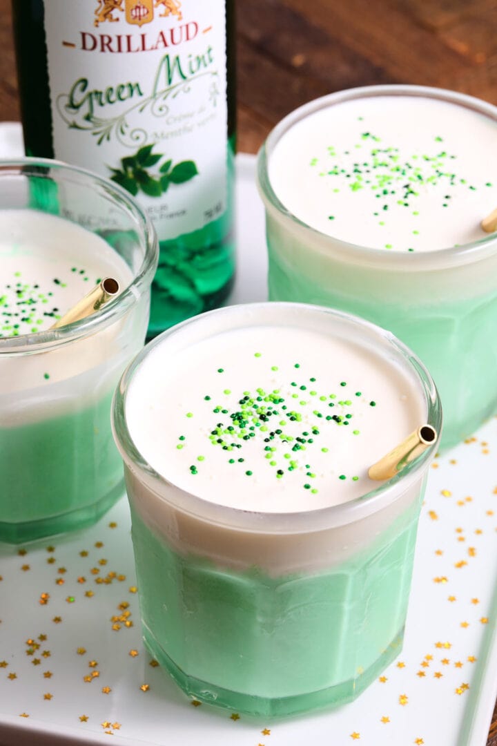 green mint milkshakes with creamy topping, green sprinkles and gold straws.