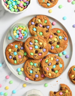 large gray plate of chocolate chip cookies with pastel colored M&Ms candies.