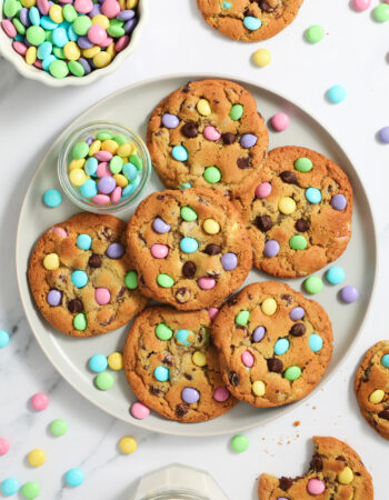 large gray plate of chocolate chip cookies with pastel colored M&Ms candies.