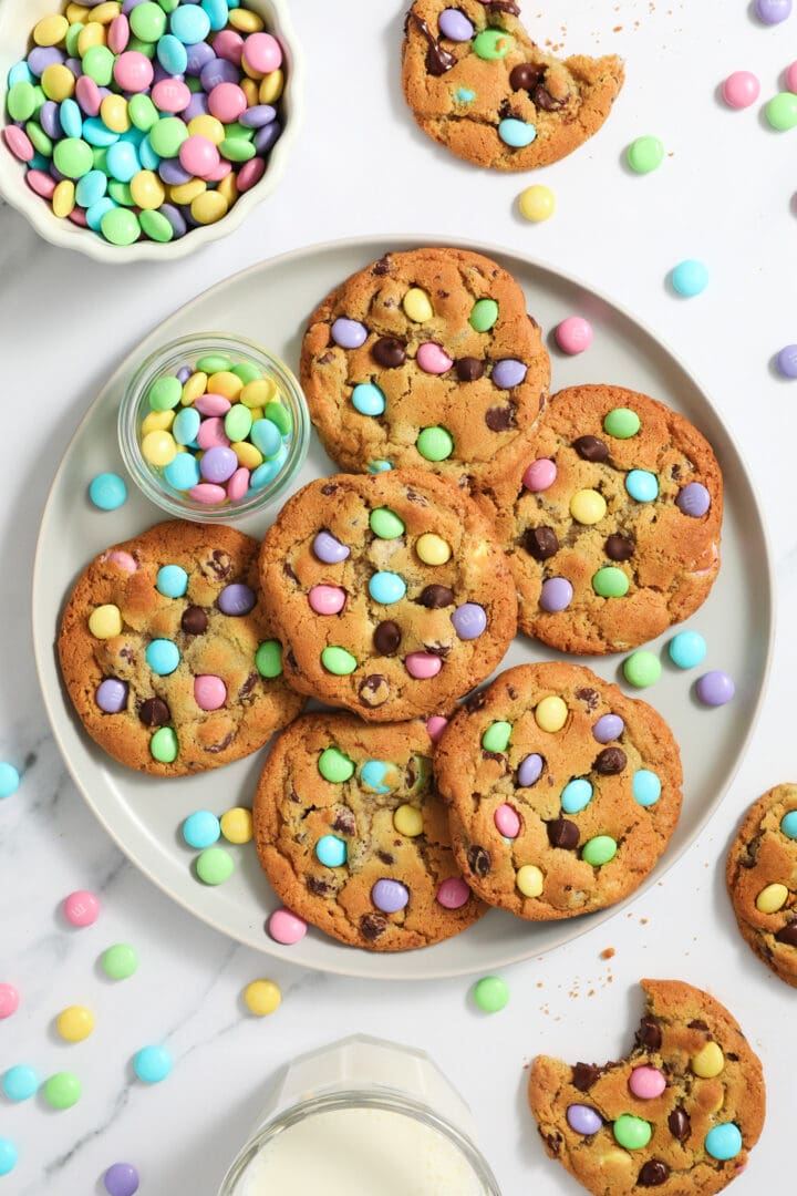 large gray plate of chocolate chip cookies with pastel colored M&Ms candies.