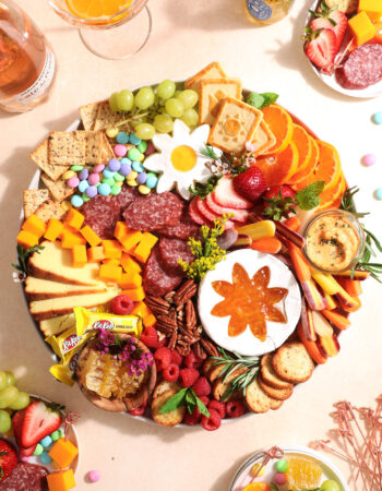 colorful charcuterie board with fresh fruit, vegetables, cookies, nuts, and cheese.