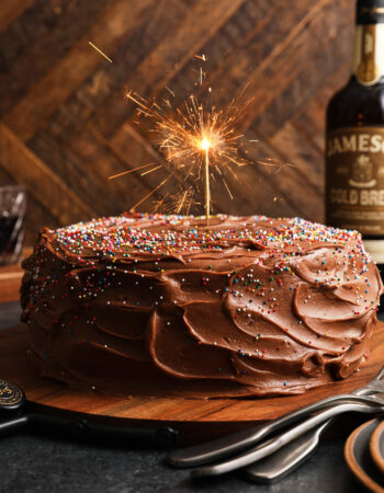 whole devil's food chocolate cake with rainbow sprinkles and a sparkler on top.