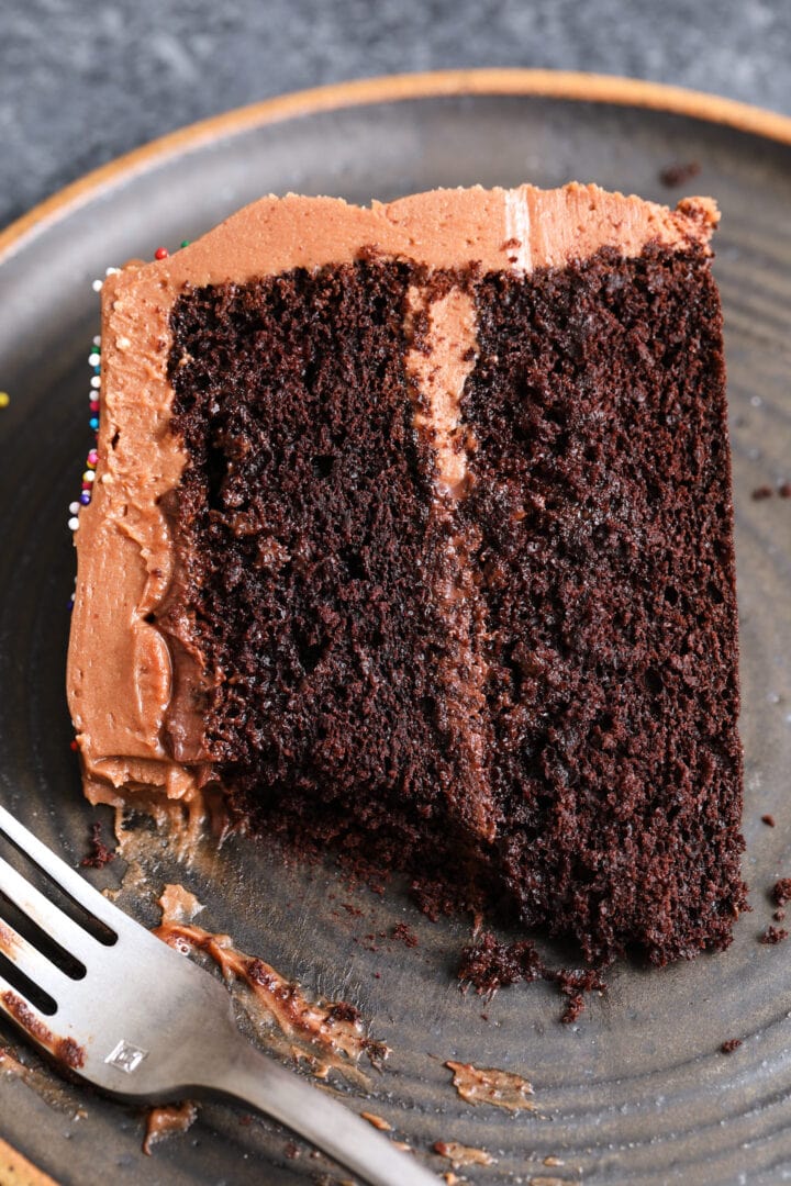 slice of chocolate devil's food cake on a black plate with a silver fork.