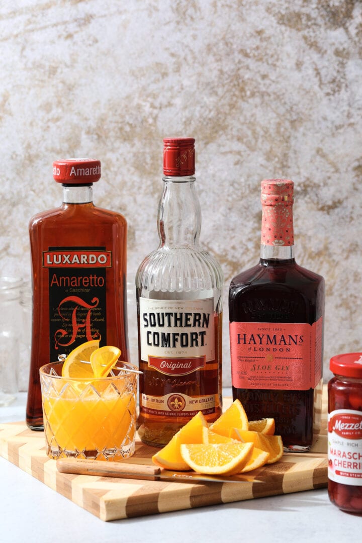 ingredients to make an Alabama slammer cocktail, including fresh orange juice, sloe gin, Southern Comfort and amaretto.