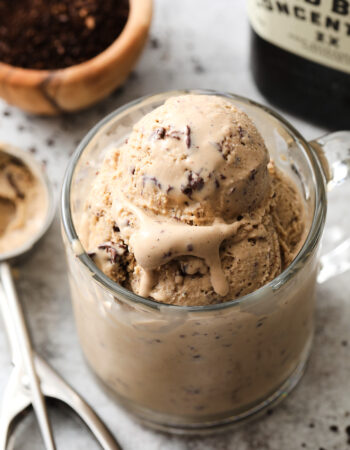 clear coffee mug with several scoops of coffee ice cream. There is a small bowl of coffee grounds off to the left.