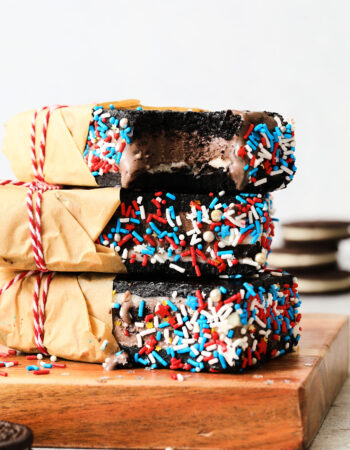 chocolate sandwich cookie ice cream bars, decorated with red, white and blue sprinkles and wrapped in brown parchment paper.