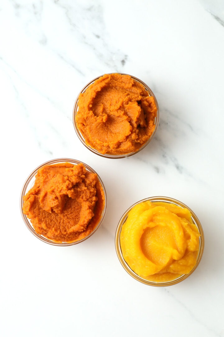 three small glass bowls of pumpkin puree, one fresh, one organic and the other canned.