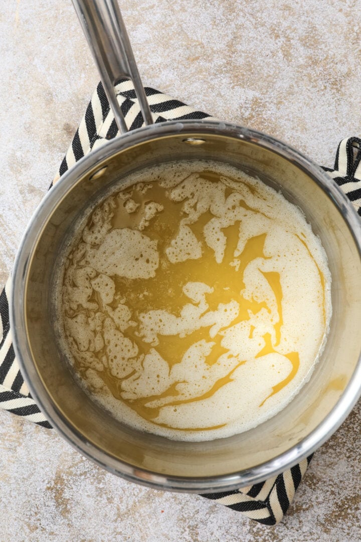 clear butter that has melted and is ready to be browned in a silver saucepan.