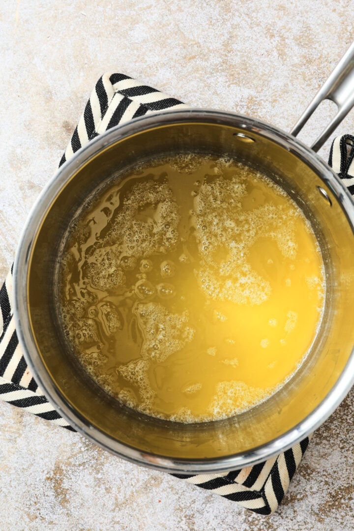 clear butter that has melted and is ready to be browned in a silver saucepan.