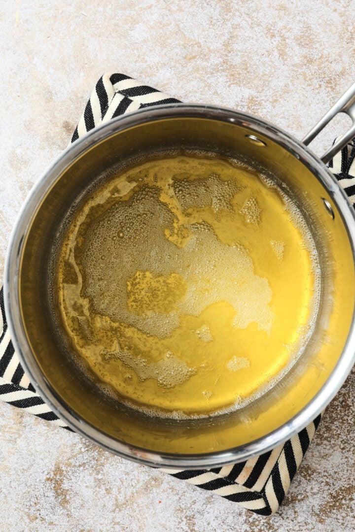 clear butter that has melted and is ready to be browned in a silver saucepan.