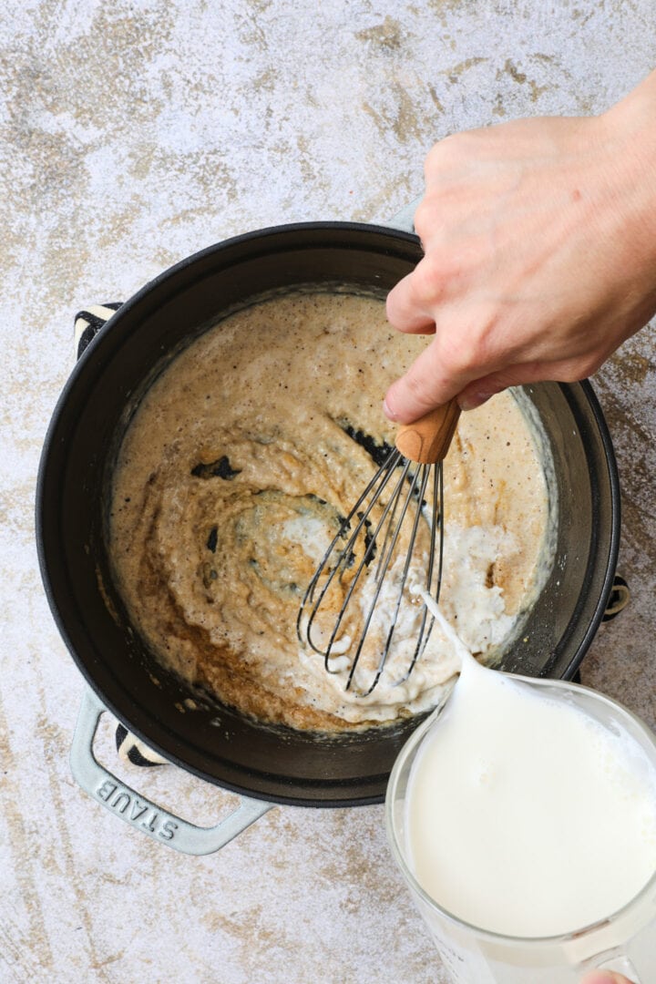 Cream being poured into the pot of seasoned flour to create a roux to thicken the sauce.