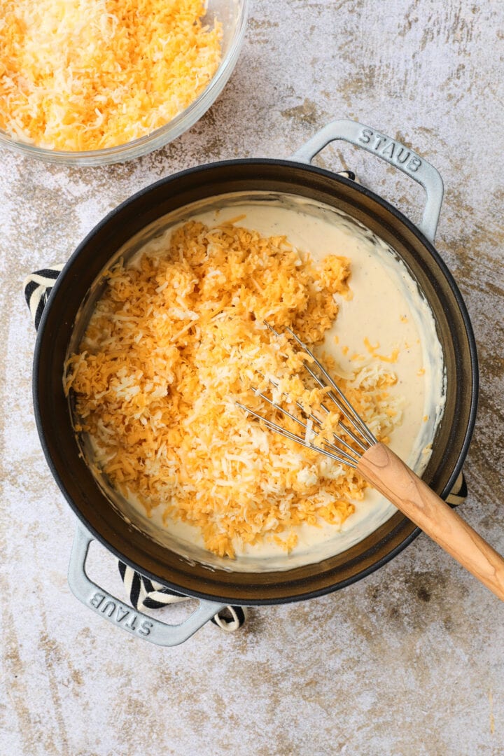 large pot of pumpkin cheese sauce, being whisked as the cheese is added in.