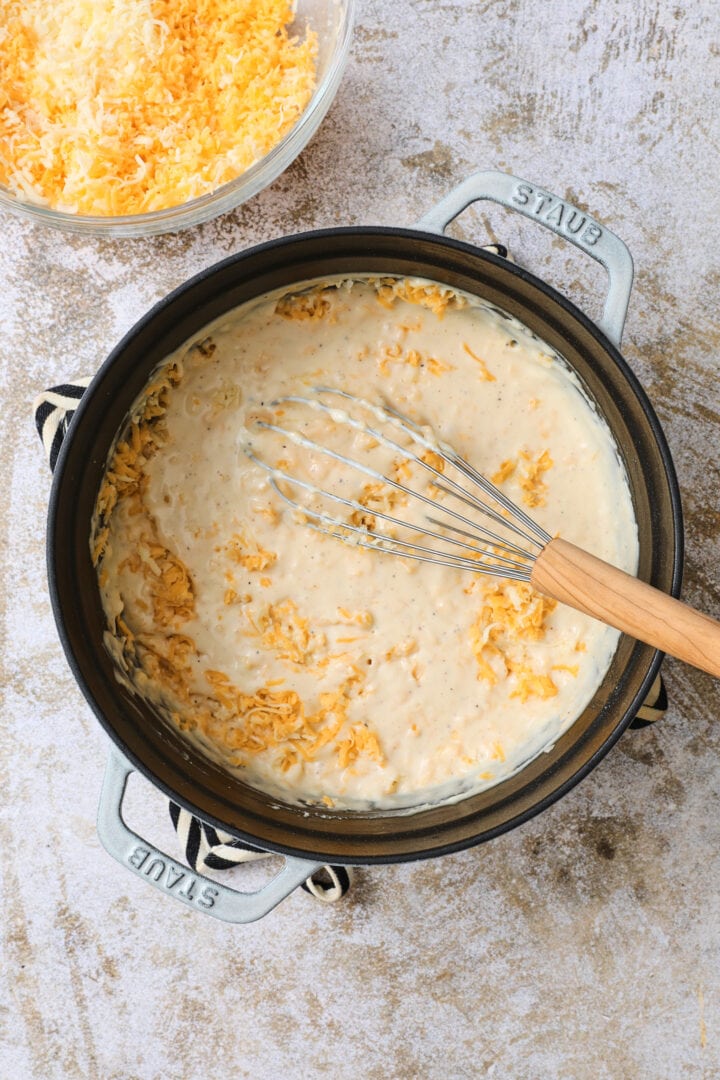 large pot of pumpkin cheese sauce, being whisked as the cheese is added in.