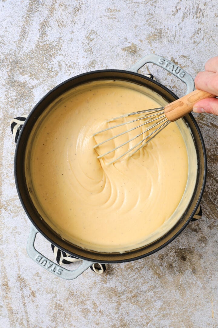 large pot of pumpkin cheese sauce, being whisked.