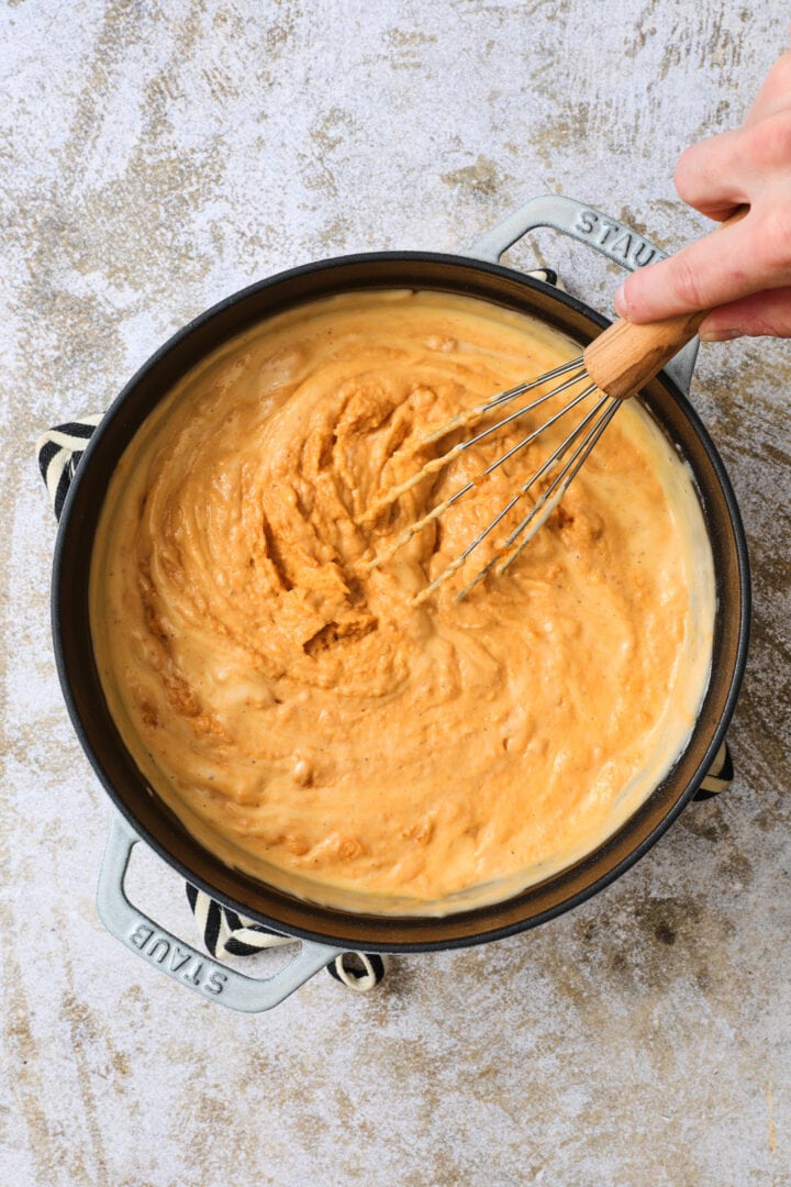 large pot of pumpkin cheese sauce, being whisked.