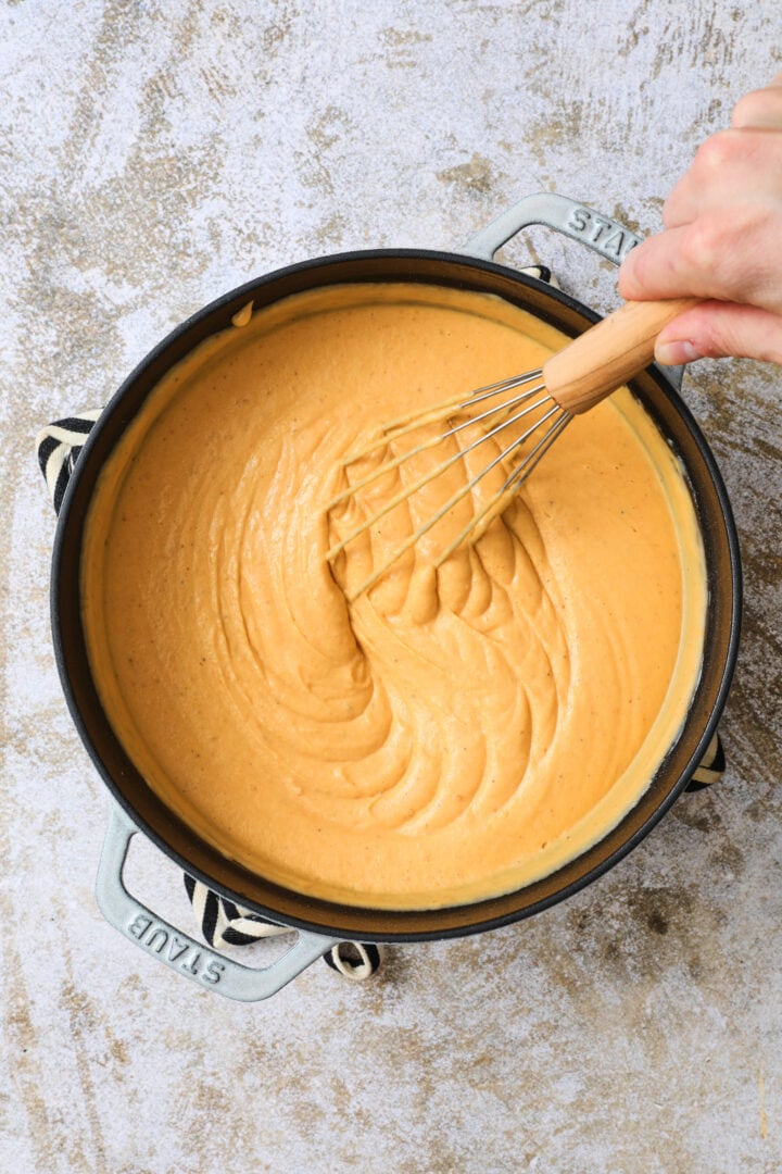 large pot of pumpkin cheese sauce, being whisked.