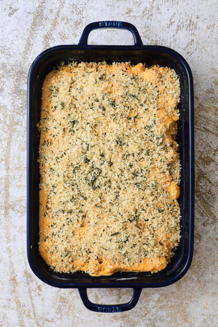 Unbaked blue pan of pumpkin macaroni and cheese, with a breadcrumb topping.