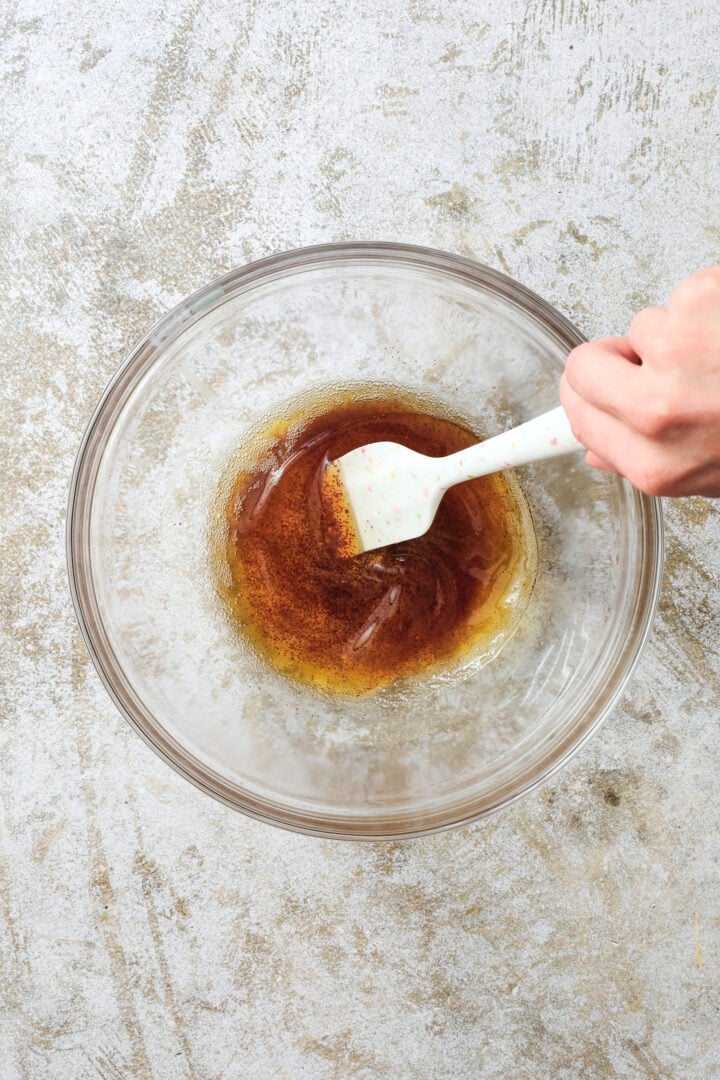 clear bowl of browned butter being stirred with a white spatula.