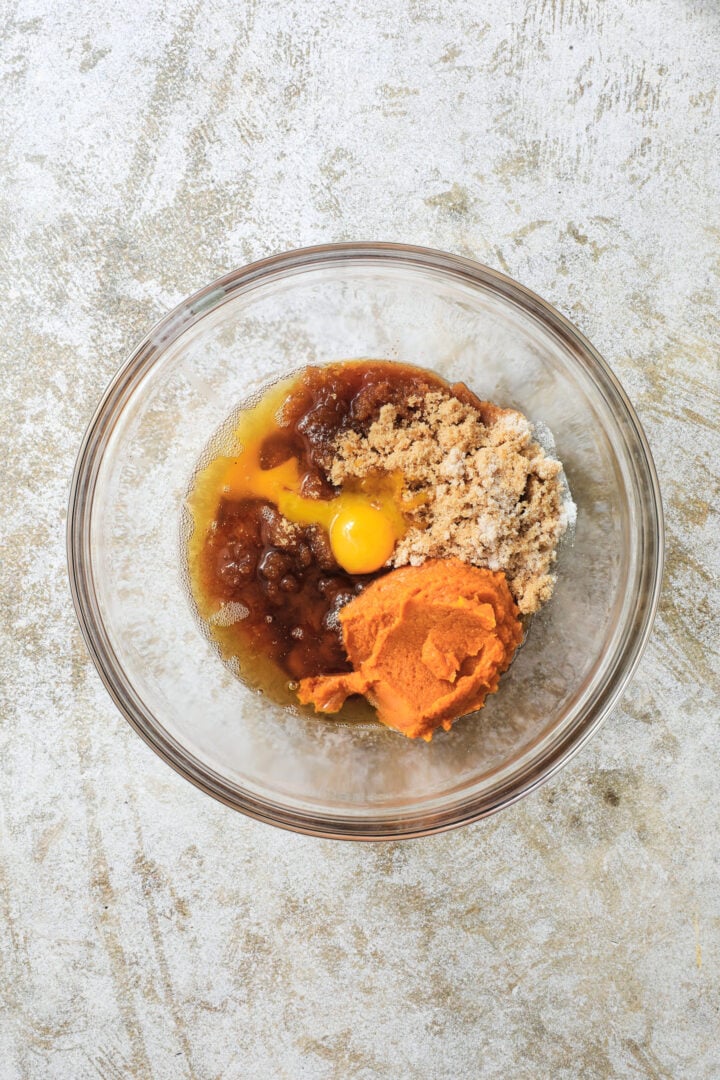 a clear bowl of unblended wet ingredients for pumpkin chocolate chip cookies.