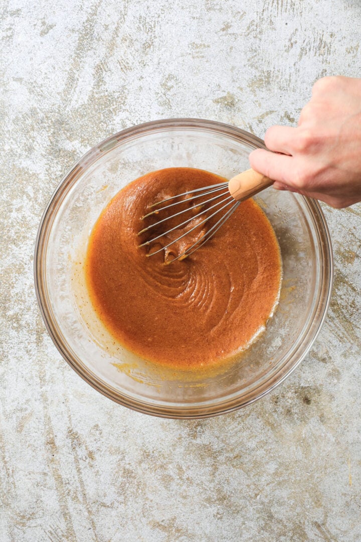 a clear bowl of blended wet ingredients for pumpkin chocolate chip cookies.