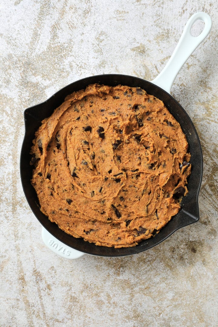 an unbaked pumpkin chocolate chip skillet cookie, ready to go in the oven.