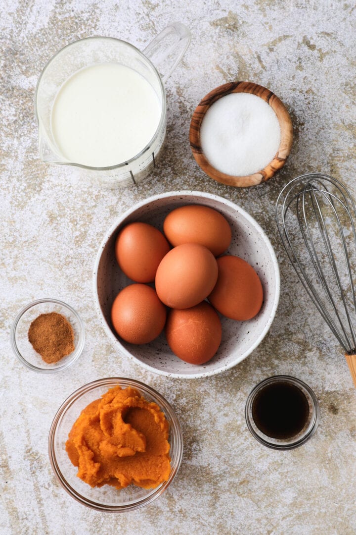 ingredients to make pumpkin creme brulee, including pumpkin, eggs, vanilla, sugar, salt and cream.