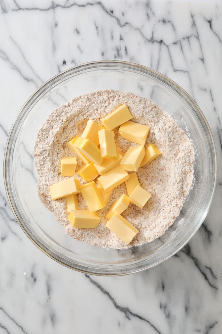 Butter and flour being mixed together in a large glass bowl.