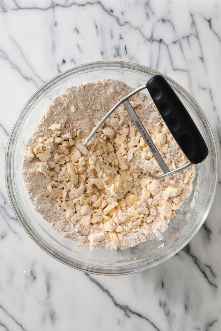 Butter and flour being mixed together in a large glass bowl.