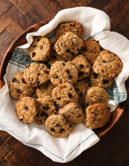 large wooden platter filled with brown bread biscuits with raisins. There is a white towel beneath the biscuits.